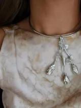 Gargantilla rígida plateada con colgante de nácar y metal plateado con forma de flores y hojas.