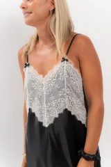 Camisón corto negro de satén con breteles finos y escote en V con puntilla blanca.