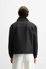 Sobrecamisa negra de corte cuadrado con cuello solapa, manga larga con puños abotonados, bolsillos de parche en el pecho, bolsillos laterales y cierre frontal con botones.