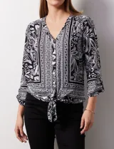 Blusa estampada con escote en V y abertura con botones. Largo de manga regulable con presilla y botón. Terminación de ruedo con nudo.