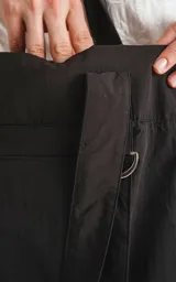 Bolso tote negro de tela técnica de microfibra de secado rápido, con espacio principal para llevar pertenencias. Cuenta con un elástico ajustable con tanca y contiene dos bolsillos, uno interno con cierre y otro externo con velcro.