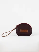 Monedero pequeño color crudo, con cierre superior y tira de cuero marrón.