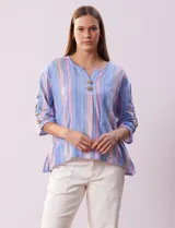 Blusa de algodón a rayas verticales en tonos celeste, rosa y blanco. Tiene cuello redondo con escote en V y abertura con botones de madera. Las mangas son 3/4 con aplique de botones.
