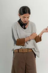 Sweater gris claro con escote en V, mangas 3/4 con puños marrones y espalda gris oscuro.