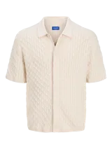 Polo de hombre color crema, tejido de punto cable, con cuello tipo polo, manga corta y cierre con botones.