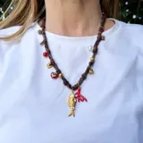 Collar corto hecho en pañuelo marrón con mix de dijes dorados, rojos y blancos.