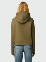 Buzo con capucha color verde oliva, con cordones ajustables y bolsillo tipo canguro. Logo bordado de corazón negro en el pecho. Corte holgado.