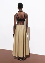 Falda larga color beige, de tiro bajo y corte evasé, con cintura elástica y bolsillos laterales.