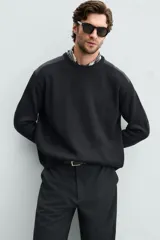 Jersey negro de punto con cuello redondo y manga larga. Presenta parches combinados en hombros y codos.