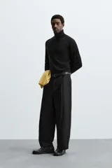 Pantalón negro de corte amplio, tipo balloon fit, con pinzas en la cintura, bolsillos laterales y traseros de ojal.