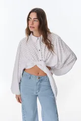 Camisa blanca con textura de lunares, corte holgado, cuello camisero y mangas largas abullonadas. Se ata en la parte delantera.