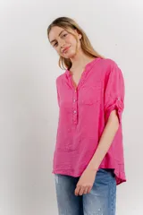 Camisa azul de lino con escote en V abotonado, bolsillo frontal y mangas 3/4 con trabilla.