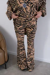 Conjunto de pantalón y camisa con estampado animal print tipo cebra en blanco y negro. La camisa es de manga larga con cierre de cremallera y el pantalón es acampanado.