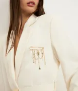 Kit de tres broches metálicos con baño dorado. Incluye un broche con forma de lazo texturizado, uno con forma de flor calada y un tercero tipo alfiler de gancho con cadenas colgantes que incorporan dijes de corazones y estrellas.