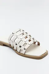 Sandalia baja negra con diseño entrelazado y apliques metálicos.