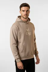 Canguro color beige con capucha, bolsillo canguro frontal y estampado de un escorpión con la palabra "CALI" y "International Club" debajo.