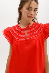 Vestido corto celeste de lino, corte suelto, con cuello redondo con volados y lazo, mangas cortas con volados.