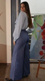 Camisa celeste con volados en el frente, cuello en V y mangas largas.
