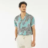 Camisa celeste con estampado de hojas de palmera en tonos negro y blanco, de corte recto, con cuello cubano y mangas cortas con dobladillo.
