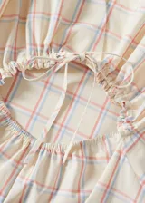 Vestido largo de algodón con estampado a cuadros en tonos beige, rojo y azul. Diseño evasé, cuello redondo y sin mangas.