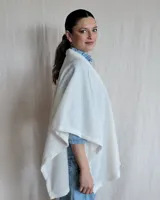 Ruana tejida con lana suave, color gris claro, con textura en relieve.