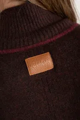 Sweater negro de tejido grueso con cuello alto acanalado. Presenta una franja decorativa en las mangas y el cuello en hilo marrón con brillo (lurex).