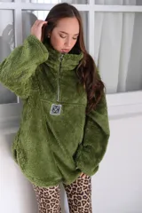 Buzo verde de peluche corderito con cierre parcial en el cuello y logo cuadrado en el pecho.