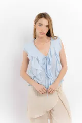 Blusa blanca de algodón con escote en V, volados en el frente y mangas cortas.