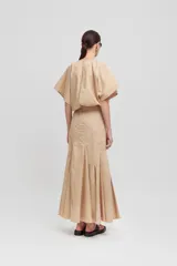Falda larga color beige, de talle alto, con aberturas verticales y bajo acampanado.