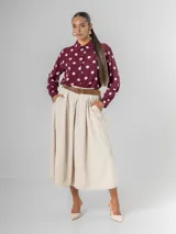 Falda midi de corderoy color beige claro, con pliegues verticales marcados y cintura elastizada. Incluye un cinturón desmontable de cuero marrón con hebilla dorada.