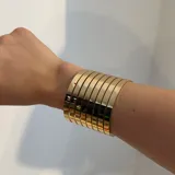 Brazalete ancho plateado, formado por múltiples bandas horizontales.