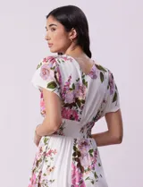 Vestido blanco con estampado floral en tonos rosados, violetas y verdes. Escote en V tanto en la parte delantera como en la espalda. Cintura elastizada con punto smock y forro interno a tono.