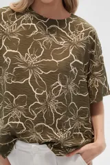 Blusa verde militar con estampado de flores blancas, de viscosa, corte holgado, cuello redondo y mangas cortas.