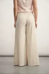 Pantalón palazzo a rayas verticales color beige y blanco, de tiro alto y corte amplio.