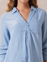 Blusa celeste de lyocell, con cuello con solapa, escote en V y abertura con botones. Mangas ¾ con puño y botón.