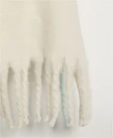 Bufanda manta de tejido suave, color blanco hueso, con flecos definidos en los bordes.