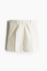 Short color crudo de lino con tiro alto, pinzas delanteras, bolsillos laterales y cierre con botón y gancho ocultos.