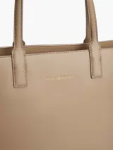 Cartera tote Tommy Hilfiger color beige con sutil acabado granulado. Cuenta con cierre de cremallera, dos asas superiores, compartimento principal, bolsillo interior con cremallera, forro con la inscripción de Tommy Hilfiger y logo de Tommy Hilfiger en la parte delantera.