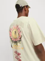 Camiseta color crema de manga corta y cuello redondo con calce holgado. Estampa en la espalda con print de goma de tacto suave.