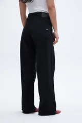 Pantalón jean negro de corte holgado con pierna ancha y tiro medio. Cierre frontal con botones a la vista.