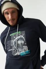 Canguro azul marino de felpa con capucha y cordones blancos. Presenta un estampado con una imagen de una escultura y texto en verde y blanco. Tiene bolsillos tipo canguro y puños y cintura acanalados.