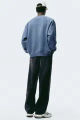 Jean negro de denim de algodón rígido, corte holgado de cadera a bajo con piernas redondeadas extraamplias y pliegues al tobillo. Cintura clásica con cierre y tiro bajo.