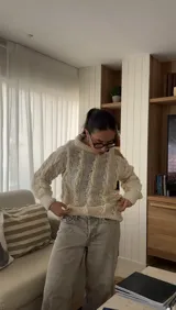 Sweater color crudo de lana merino con cuello alto y un solo hombro al descubierto, tejido a mano.