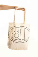 Bolso de mano tipo tote bag color crudo, con asas largas y logo estampado en negro.