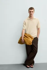 Polo color beige de punto con cuello solapa y manga corta.