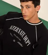 Remera deportiva negra de manga corta con cuello redondo y estampa frontal en relieve con la frase "Alternate Dept Collection Revealing the unknown Powered by Dreamerland".
