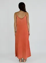 Solera larga color crudo, con escote en V y tirantes finos. Presenta un volante vertical con efecto arrugado que recorre el frente de la prenda.