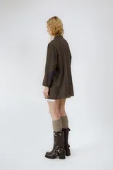 Bota de cuero color marrón oscuro, de caña media, con punta cuadrada y taco bloque. Presenta correas de cuero con hebillas metálicas plateadas alrededor del tobillo y en la parte superior de la caña.