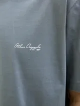 Remera azul con estampado de una mesa con sillas, una planta y luces colgantes.