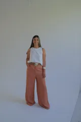 Pantalón de lino color terracota, de corte palazzo y cintura alta con cinturón de soga trenzada.